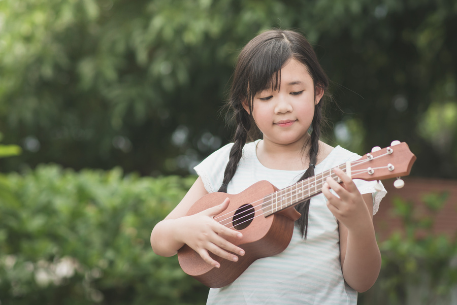 Beautiful asian girl playing ukulele,